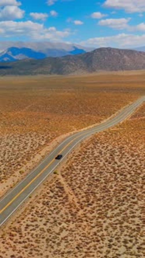 Lonely black car on the road to Nevada, USA. Beautiful sight of desert contrasting with blue skies