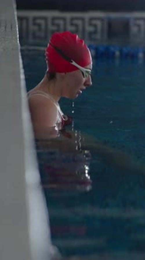 Focused Swimmer in Red Cap Preparing at the Pool Edge Gathering Concentration and Calm Before a
