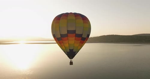 Hot Air Balloon Flying Over Lake at Sunrise