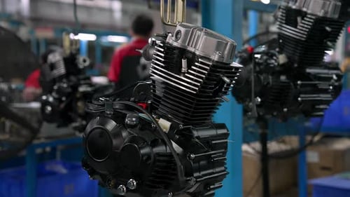 Closeup of Finished Motors on Factory Assembly Line with Workers in Background