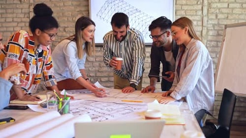 Group of young business people discussing architectural designs in office.