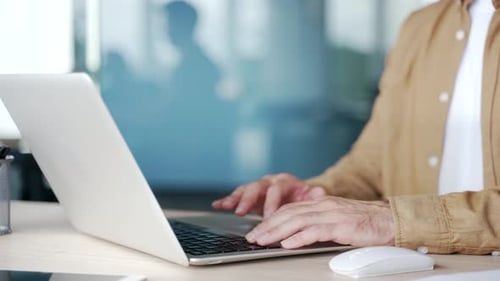 Close up of male hands typing on laptop keyboard in modern office. A businessman works on a computer