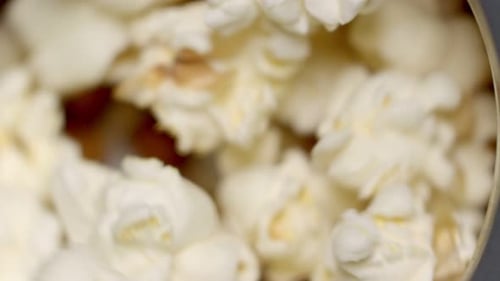 Extreme close up slow motion: Popcorn spins and pops in popper, narrow focus.