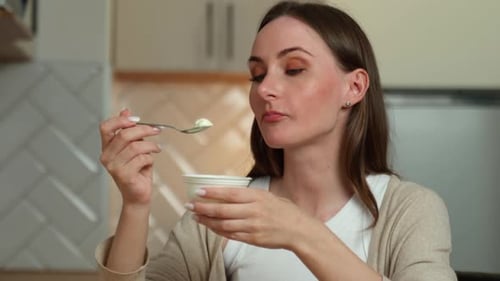 Woman Eats Creamy Yogurt in Modern Kitchen