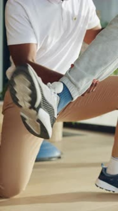 Adult Stretching Child's Leg in Home Exercise Setting