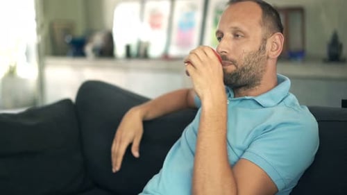 Man Relaxing on Sofa Drinking from Red Cup