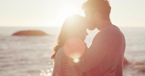Romantic, happy and hugging young couple sharing a beautiful moment on a beach sunset date