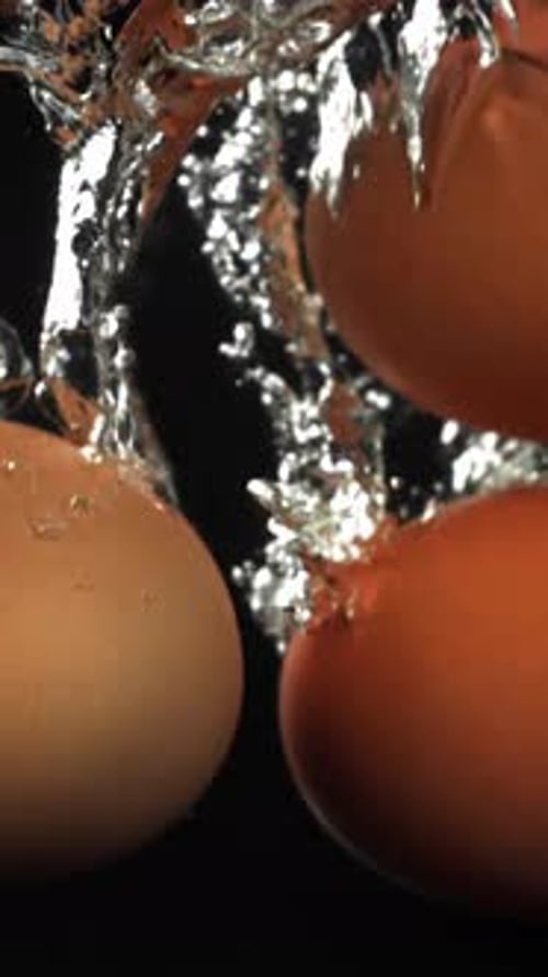 Eier, die auf schwarzem Hintergrund unter Wasser fallen, gefilmt mit einer Hochgeschwindigkeitskamera mit 1000 Bildern pro Sekunde