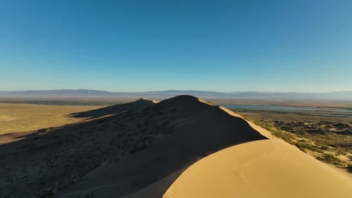 Panoramic desert dune landscape with distant mountains and water