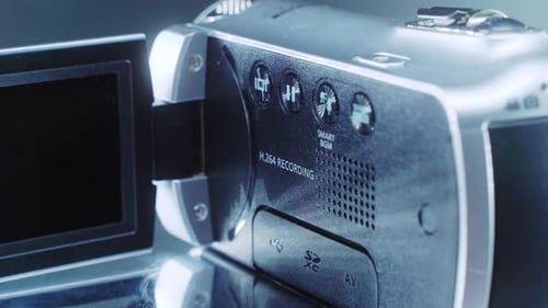 A close up shot of a video camera, silver camcorder on a 360 rotating stand, studio lighting, slow m
