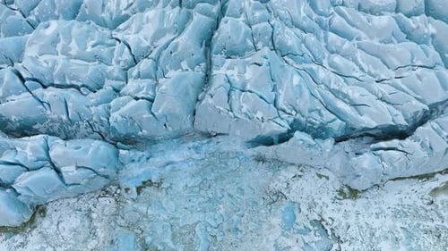 Aerial view tilting in front of a large glacier ice wall, in cloudy Vatnajokull, Iceland