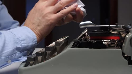 Man Inserts Wrinkled Paper into Vintage Typewriter