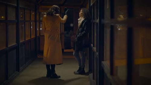 Two Women Talking in Urban Covered Walkway at Night