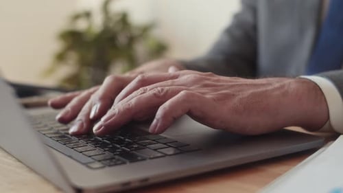 Pensive Male Entrepreneur Typing Email on Laptop Working at Office