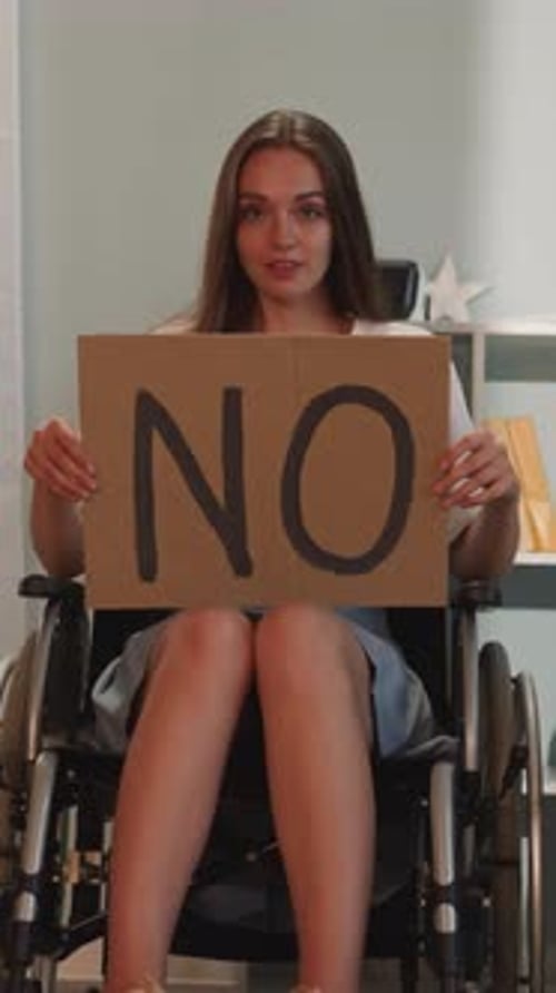 Woman in Wheelchair Holds Up Sign Saying No