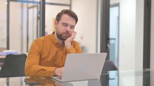 Geschäftsmann schläft ein, während er am Laptop arbeitet