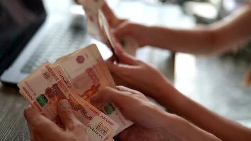 Closeup of Two Successful Business Partners Counting Russian Rubles Banknotes and Analyzing Stock