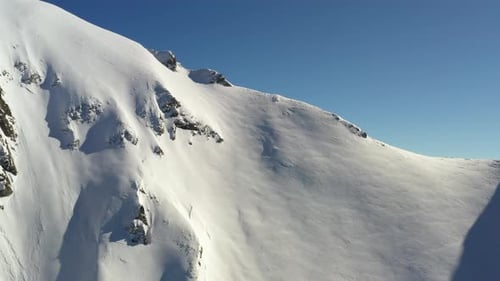Les prises de vue aériennes volant vers une crête enneigée avant de se soulever pour révéler la vallée derrière elles incluent