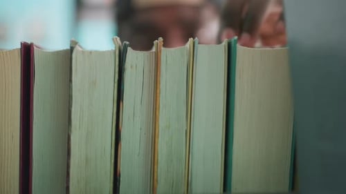 Close Up Books On Shelf With Person Taking One In Library