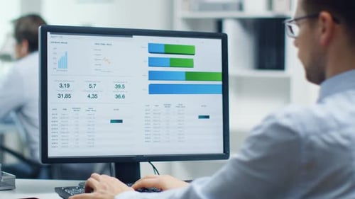 Man Analyzes Data and Graphs at Computer Workstation