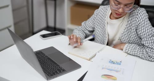 Woman Working at Desk Writing in Notebook