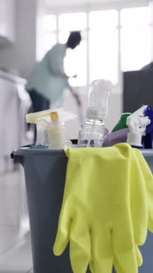 Cleaning Supplies with Person Mopping in Background