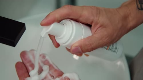 Man Applying Foam Cleanser From Dispenser Bottle