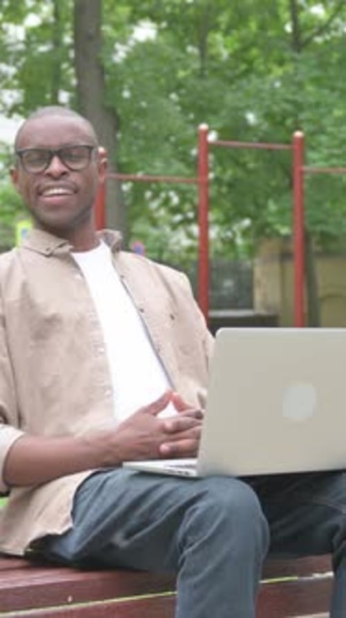 Man Using Laptop on Park Bench in Daytime