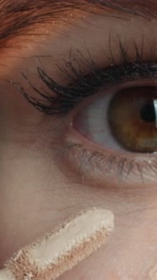 Frau trägt Concealer mit Applikator auf die Haut unter den Augen auf