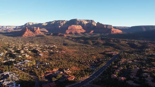 Luftaufnahme des berühmten Sedona, Arizona, USA, an einem sonnigen Morgen, Straßenverkehr und Gebäude unter Red Roc