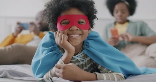 Smiling Child Lying on Bed with Family
