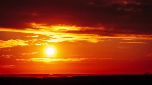 Zeitraffer eines Dramatisch Sonnenuntergangs durch Wolken am orangefarbenen Himmel über dem Horizont
