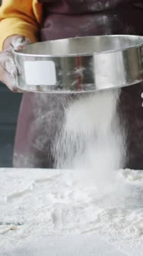 Person Sifting Flour in a Kitchen
