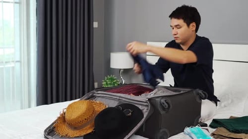 Man Packing Suitcase in Bedroom Getting Ready to Travel