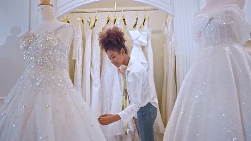 African American female designer designing bridal gown in wedding studio.