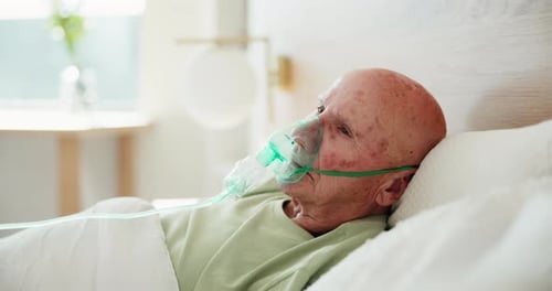 Senior Man with Medical Mask Lying in Hospital Bed