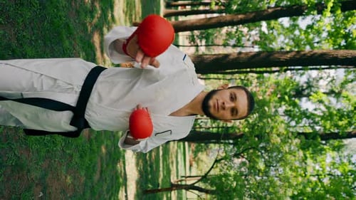 Vertical Video Outdoors in the Park in Sunny Weather Young Karate Guy Dressed in Red Combat Boots