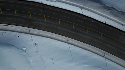 Aerial View of Winding Highway Through Snow-Covered Mountains