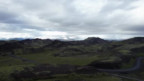 Aerial shot sweeps along a rural road running through a dramatic volcanic landscape in Iceland