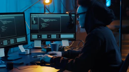 Concepto de ciberdelincuencia, piratería informática y tecnología: un hacker asiático con gafas escribiendo