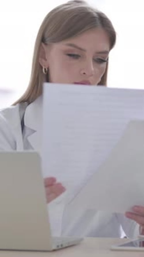 Lady Doctor travaillant sur un rapport médical et un ordinateur portable dans une clinique, Vidéo verticale