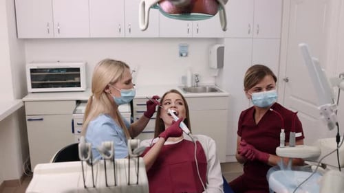 Dentist Examining Patient with Assistant in Office