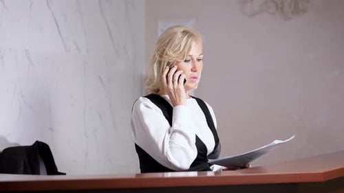 Professional Woman Talking on Phone at Reception Desk
