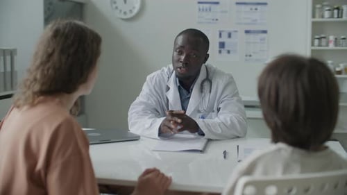 Black Pediatrician Speaking with Mother and Kid in Medical Office