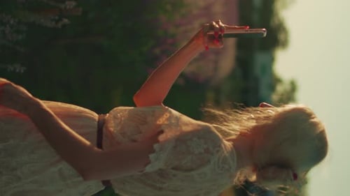 Young Blond Woman Taking a Picture with a Smartphone in the Floral Field