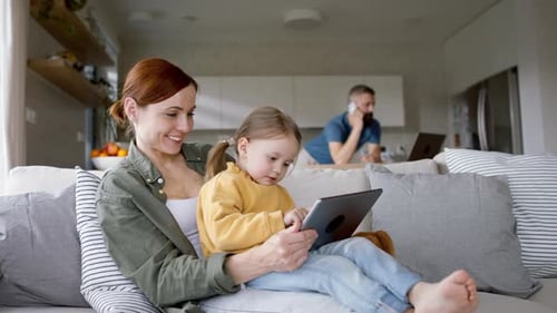 Mother and Daughter on Couch with Tablet Indoors