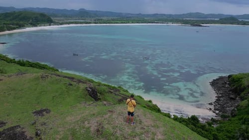 Man Looks at Scenic Tropical Bay From Hilltop
