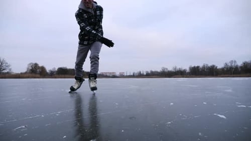 Man Ice Skating on Frozen Lake in Winter