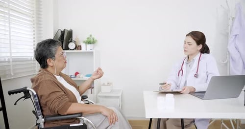 Doctor Talking with Senior Woman Patient in Wheelchair