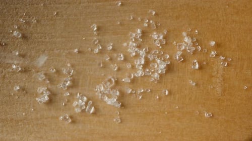 Sugar crystals fall on the wooden surface, top view. macro.
